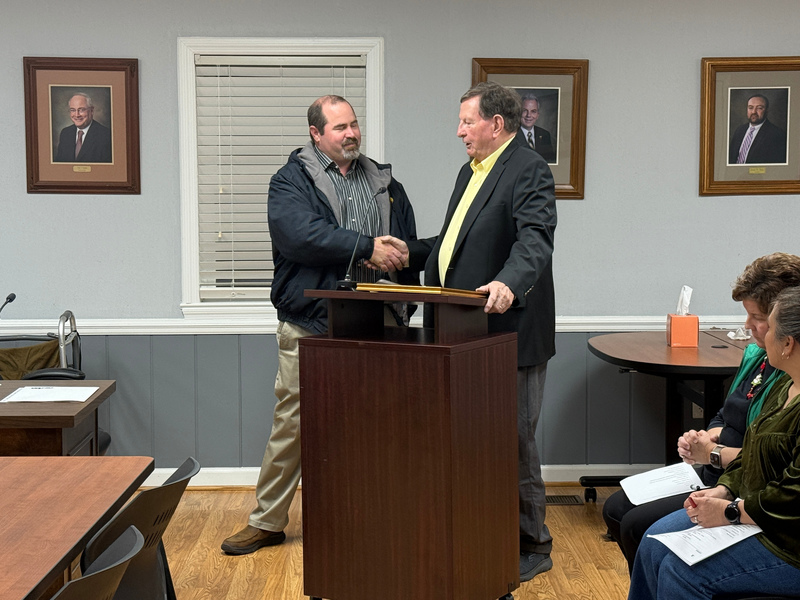 Steven Elllis shakes hands with Board Chair Dr. Mike Williams