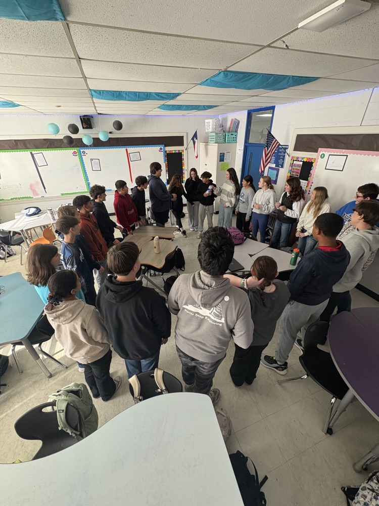 students in a circle passing a container around