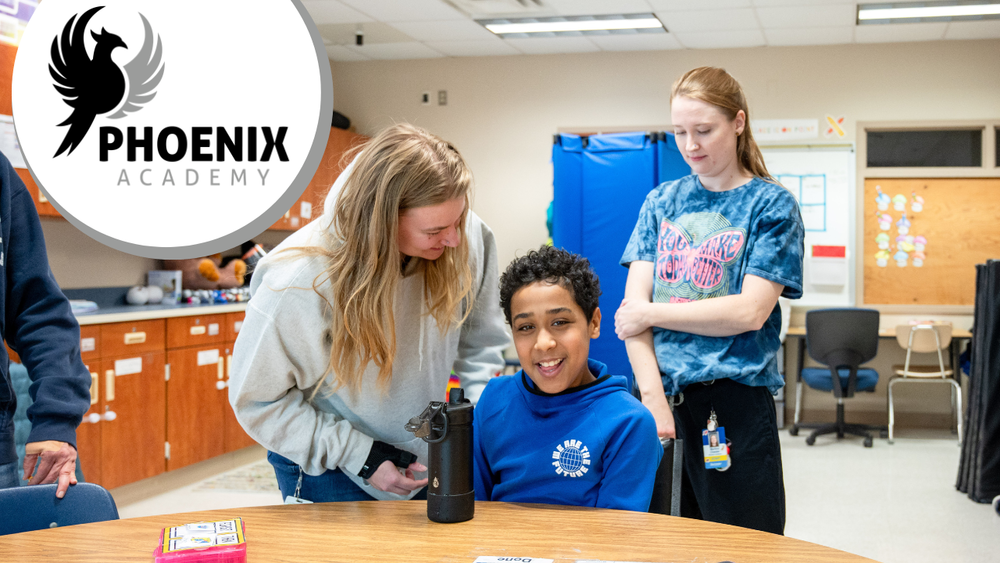 Phoenix logo overlay on image of teacher and student  laughing together with an esp in the background.