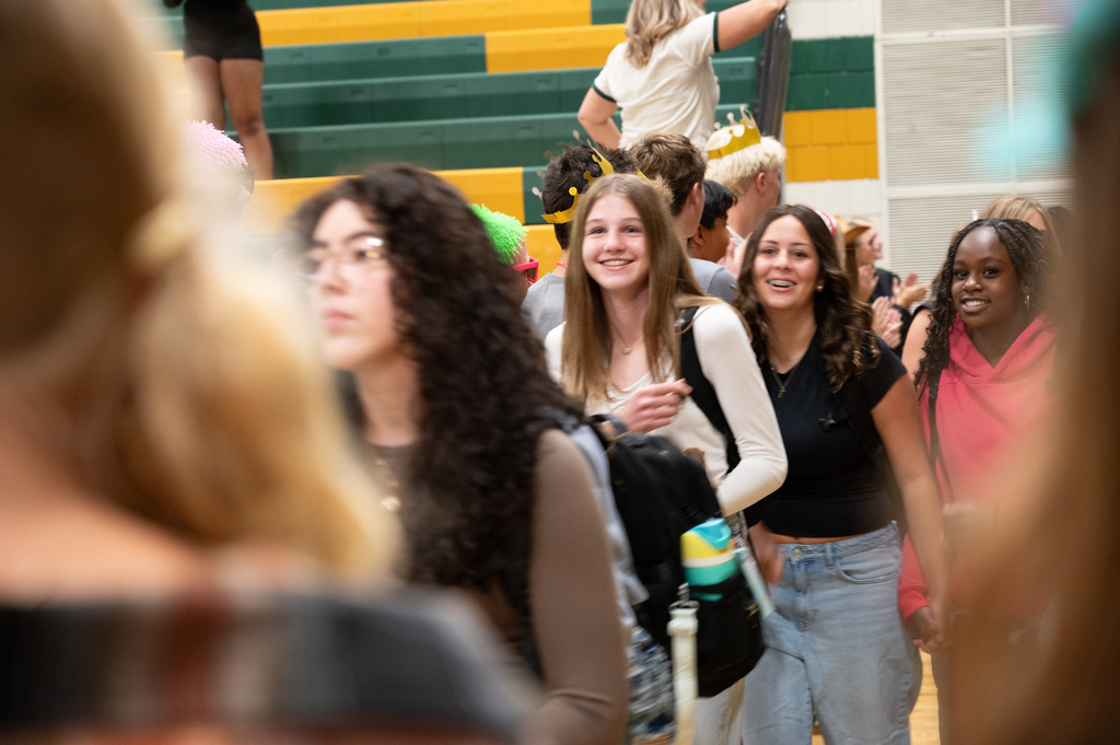Students walking through the welcome "gauntlet" of students and staff welcoming them in the Mayo gym.