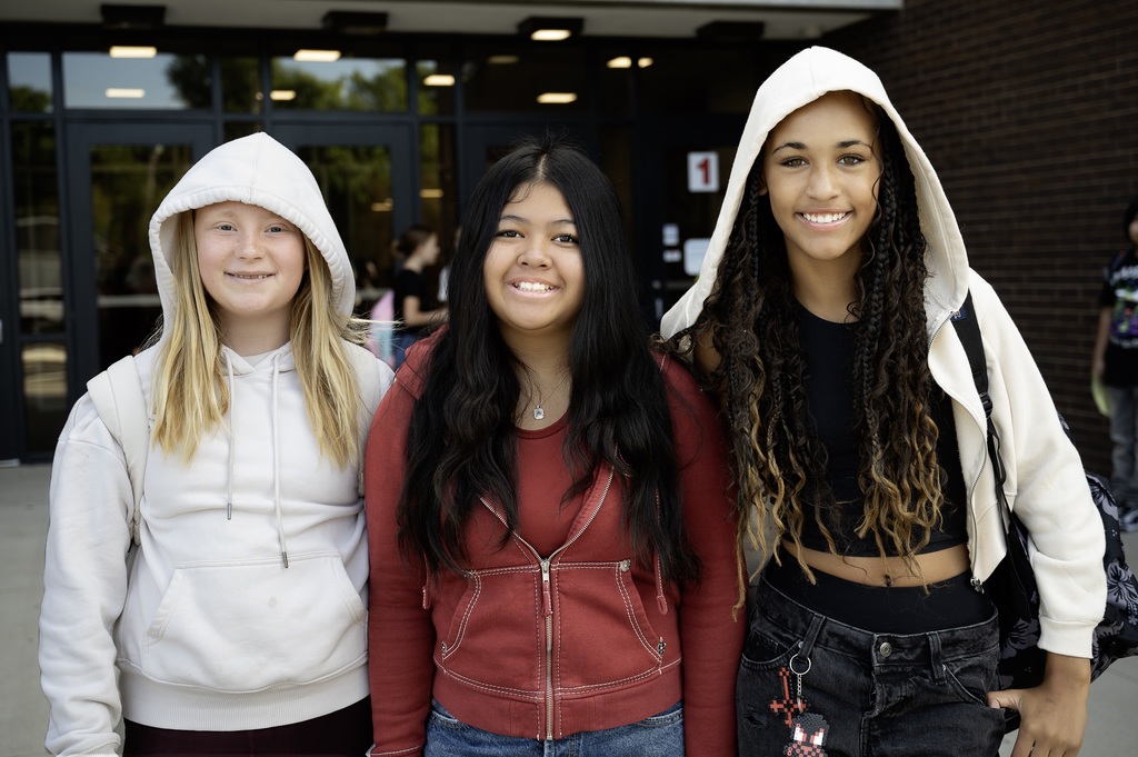 Three students at JA posing for a photo outside of the front doors.