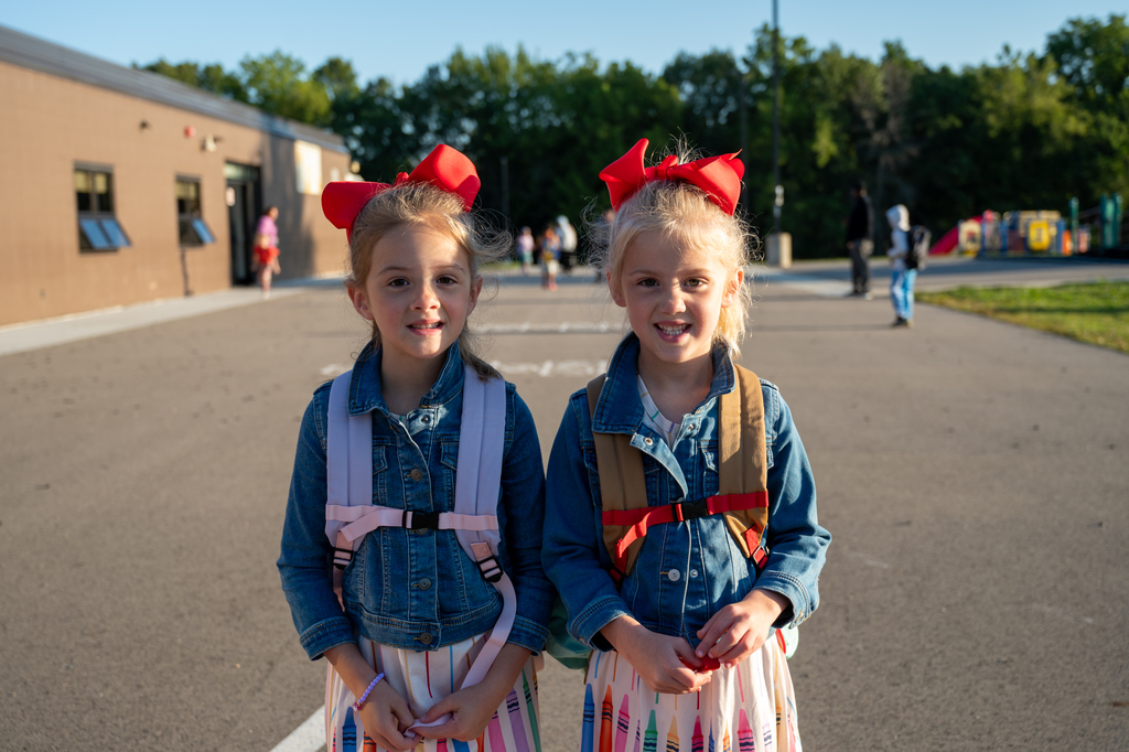 twins wearing matching red bows in their hair on their first day