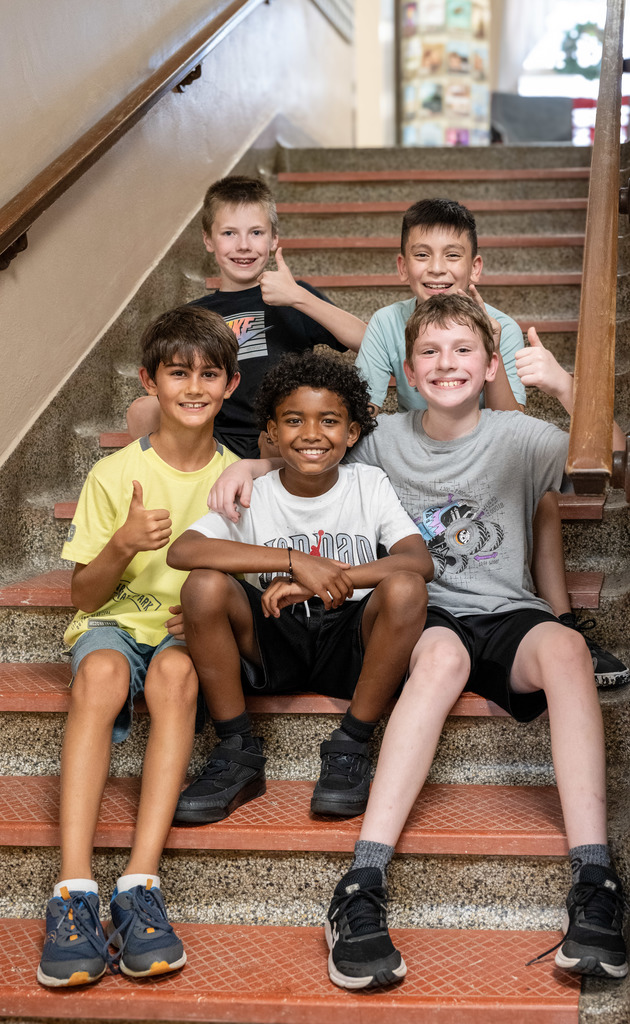 Group of students smiling at the camera while sitting in a stairwell
