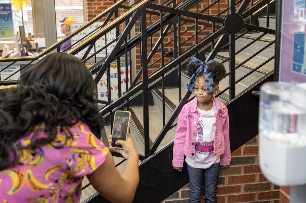 Mom taking a photo of their student on the first day of school
