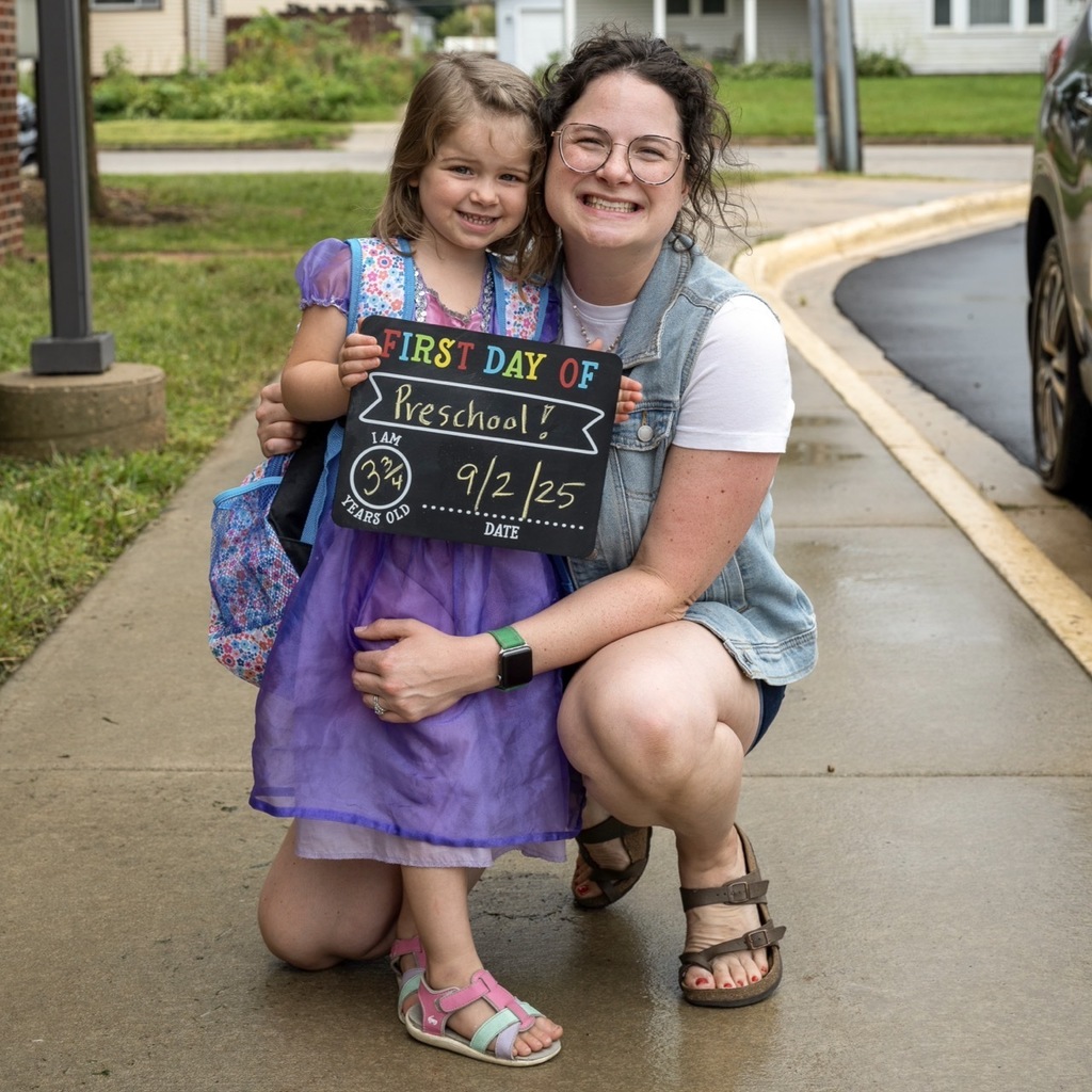 Preschool parent with child posing with a first day of preschool sign