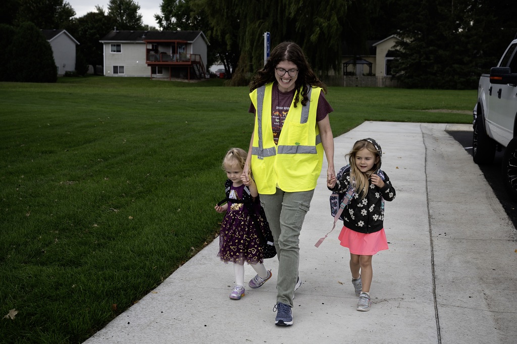 Teacher helping two students to the door for the first day of school.