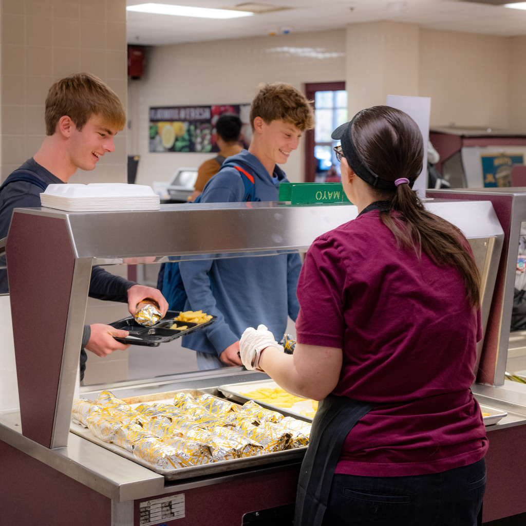 Two high school students are served wraps by Student Nutrition Services employee.