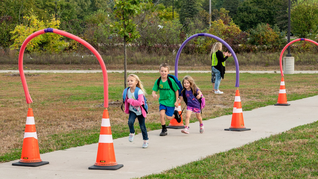 Students race through arches made of pool noodles and traffic cones.