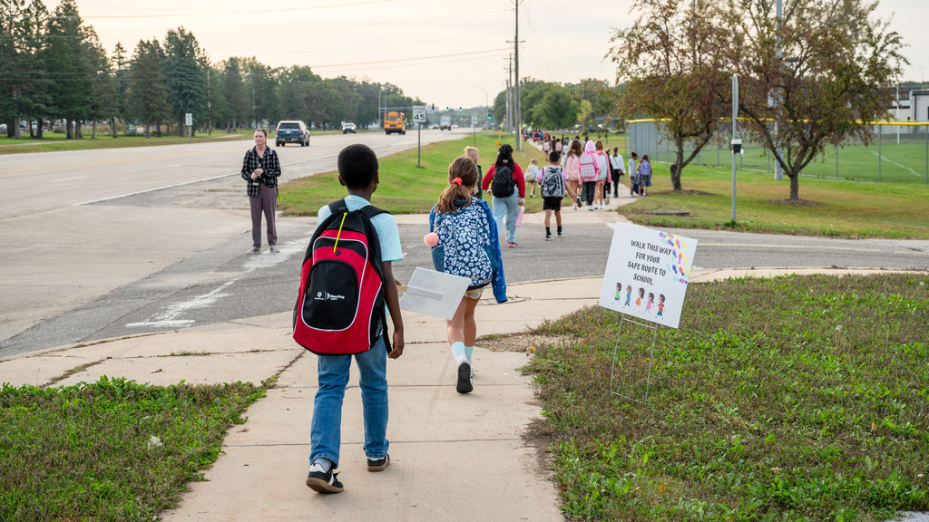 A long line of students with backpacks on the sidewalk.