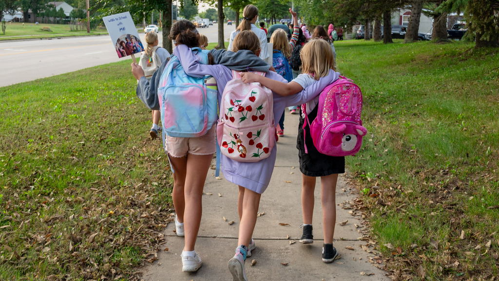 Three students walk arm-in-arm.