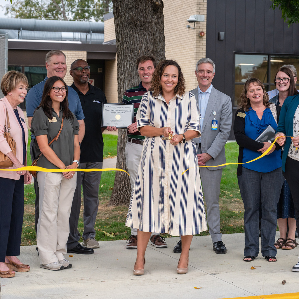 Erica Schumacher cuts the ribbon to open the new Mighty Oaks Early Learning School with supporters smiling behind her.