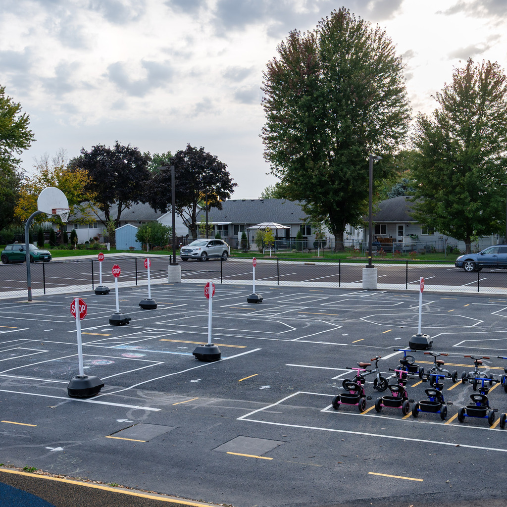 A parking lot turning into a traffic garden with scooters and painted roads on the blacktop.