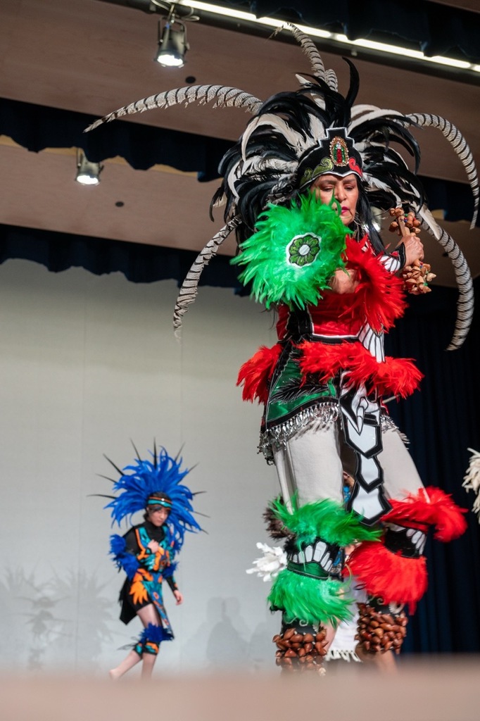 Aztec dancer in green and red with her bells in her hand