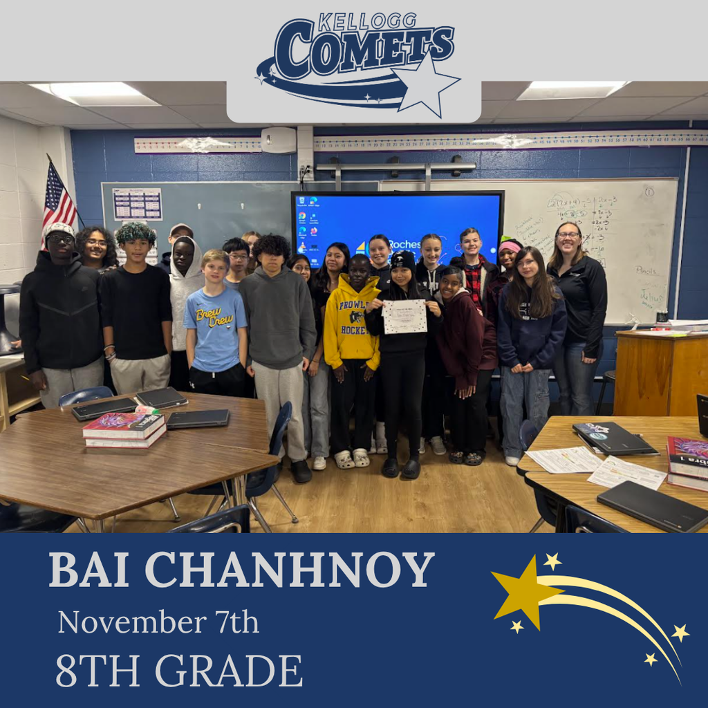 classroom of students in multicolored clothing, student in middle holding certificate for student of the week
