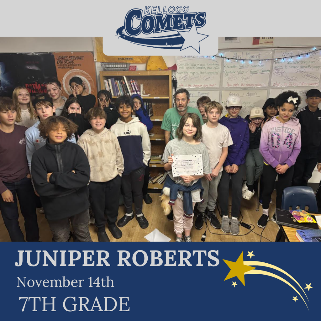 classroom of students in multicolored clothing, student in middle holding certificate for student of the week
