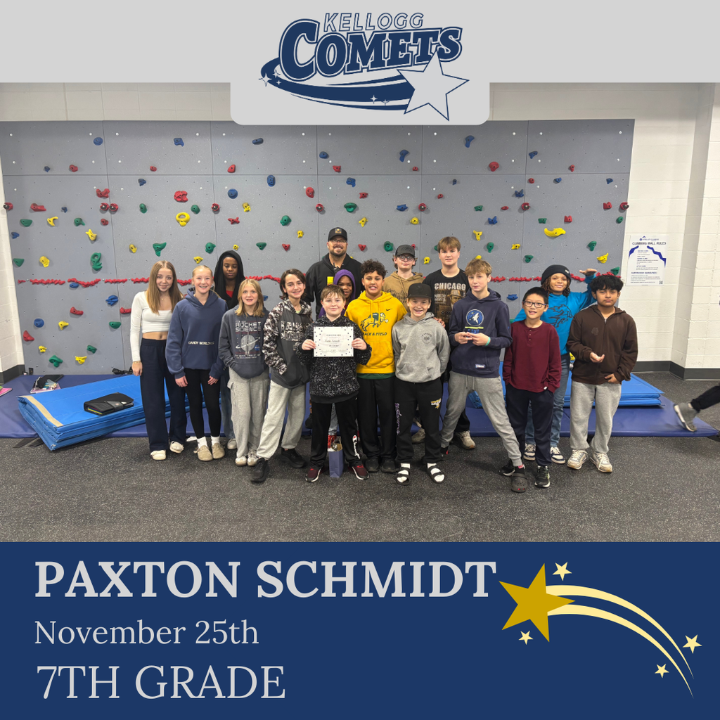 classroom of students in multicolored clothing, student in middle holding certificate for student of the week