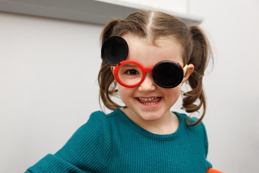 girl smiling with early childhood screening glasses on.