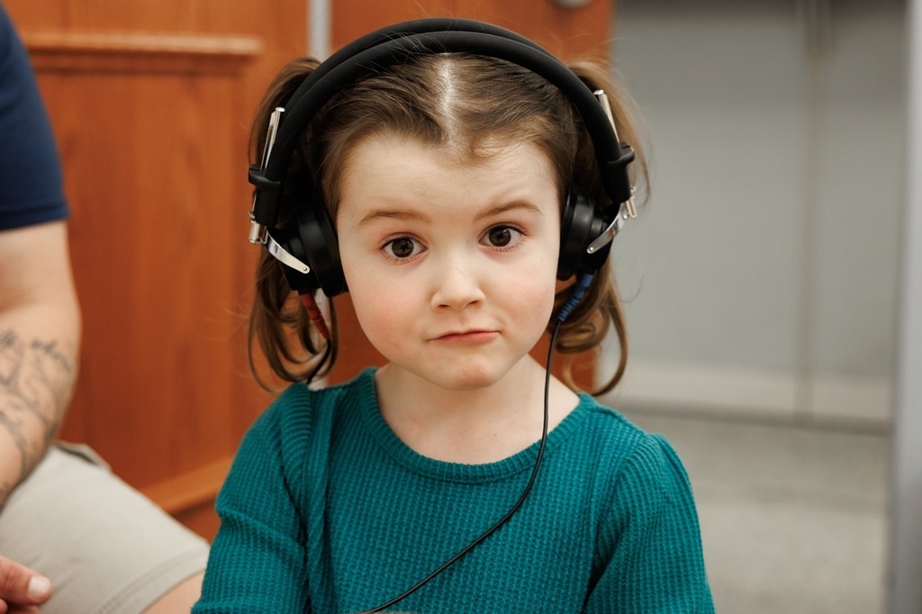 Girl with headphones on for the hearing portion of an early childhood screening.