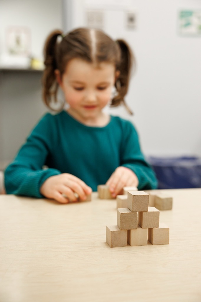 girl creating a pattern of blocks for the early childhood screening.