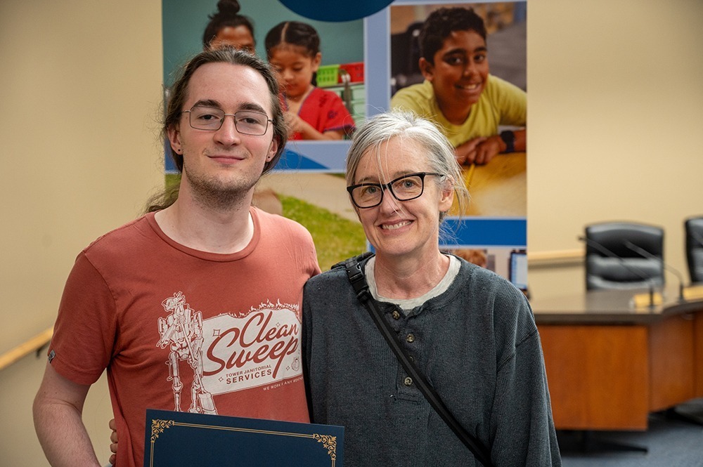 Mother and son standing for a photo with the signing certificate.