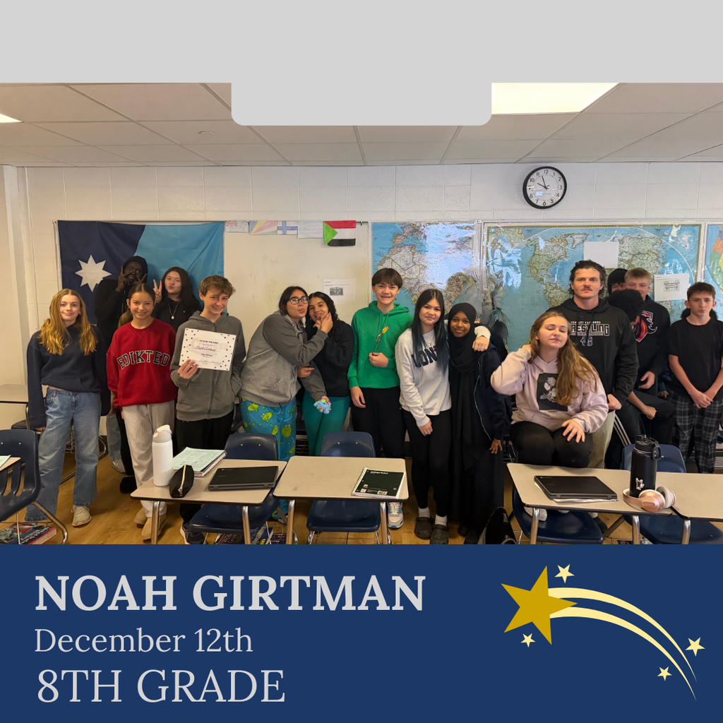 classroom of students in multicolored clothing, student in middle holding certificate for student of the week