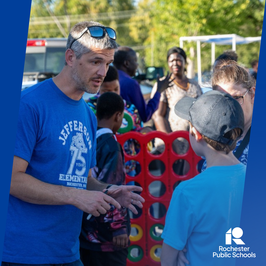 School Board Member Justin Cook talking to a family at the Jefferson 75th Anniversary event outside in the parking lot.