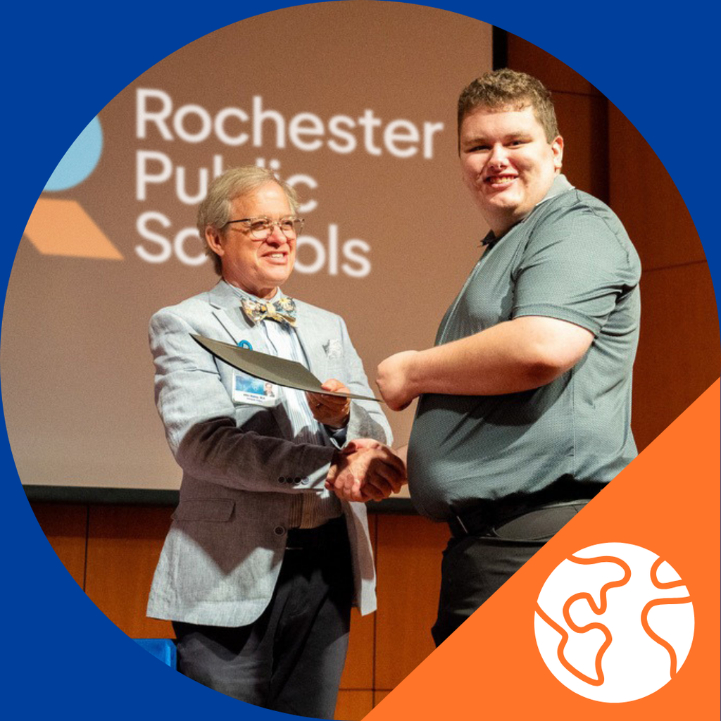 Student shaking hands with Mayo staff with the certificate of completion of the Project Search program on stage.