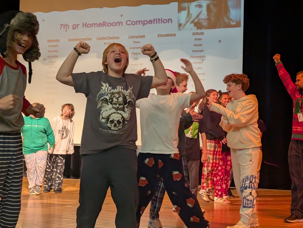 Students and staff wearing colorful clothing cheer and smile enthusiastically during a school competition, celebrating wins together in a lively, joyful atmosphere.