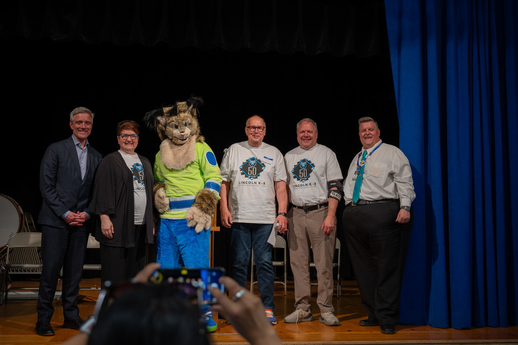 Three of Lincoln's last principals and Superintendent and School Board Chair smiling on stage