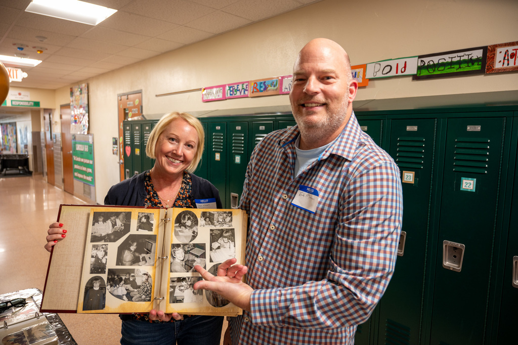 Man pointing at an image of himself in an old Jefferson yearbook while in the hallway.
