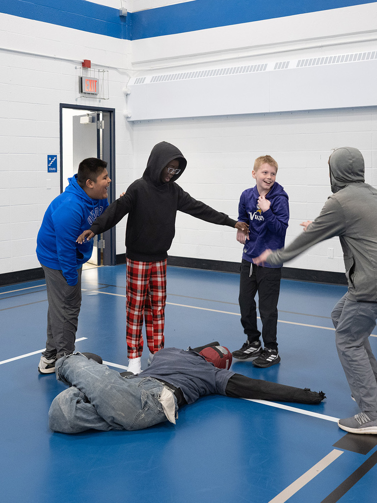 Middle school students play with a training dummy as they learn about firefighters in physical education class.