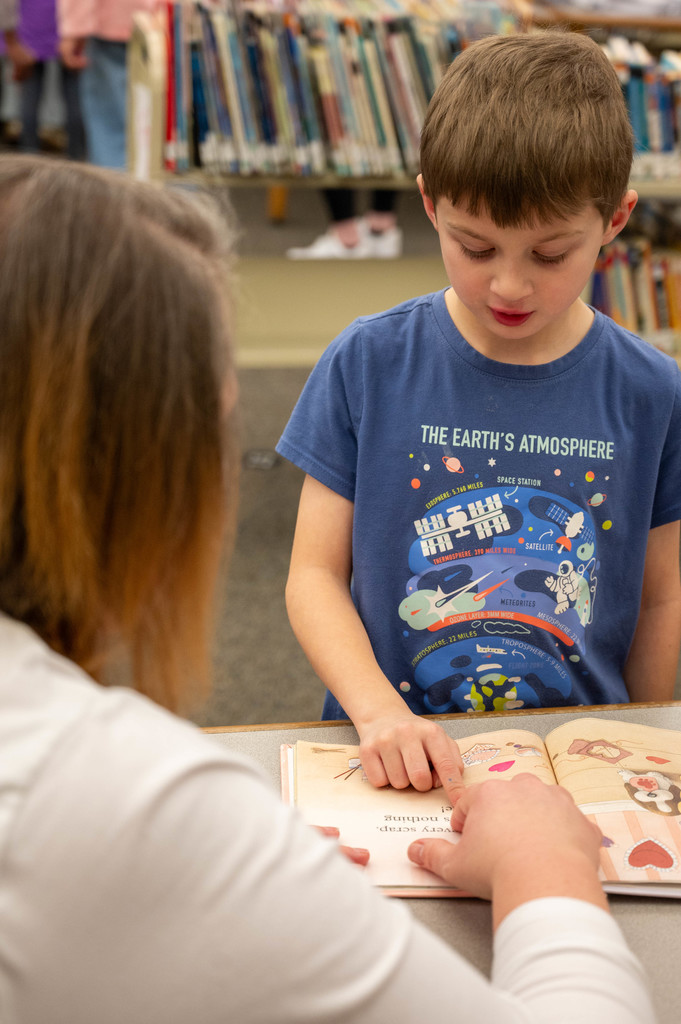 A teacher reads with a student 