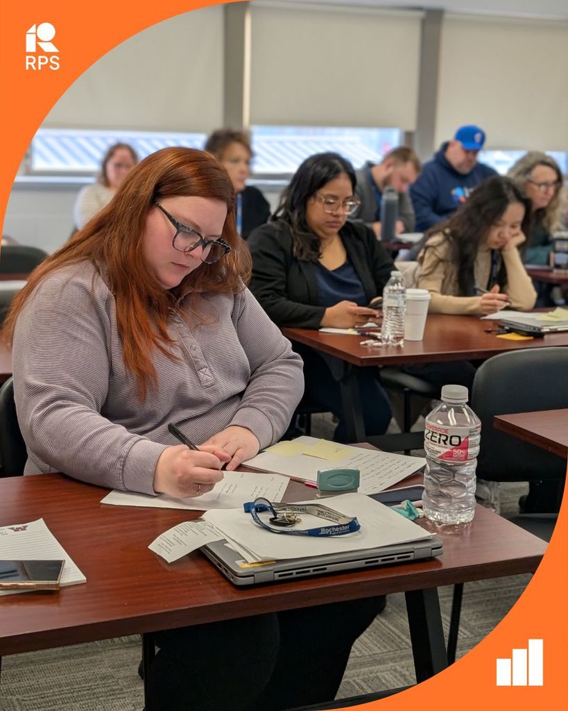 Adults journal their reflections in a classroom.