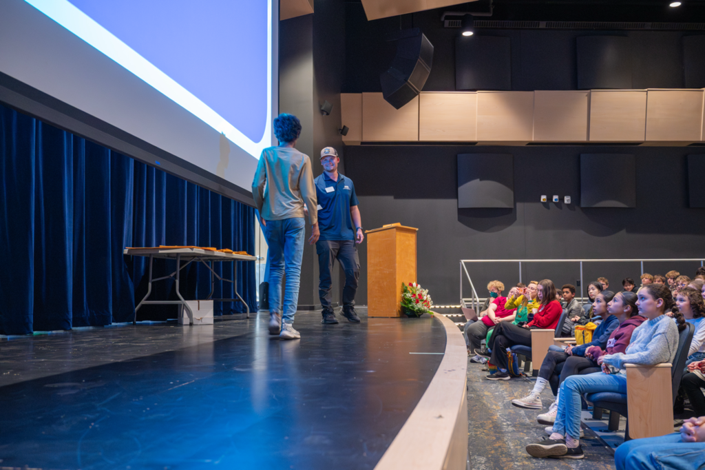 Student accepting an award on stage at the award ceremony in the Dakota auditorium. 