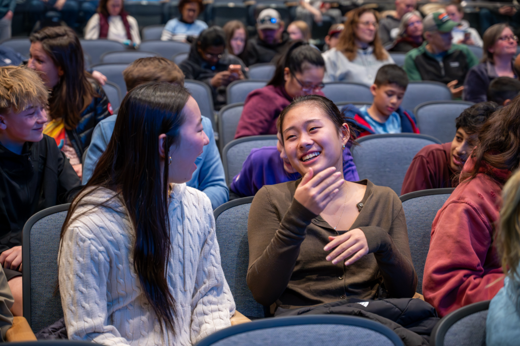Two students smiling and in shock they they won an award at the award ceremony in the Dakota auditorium 
