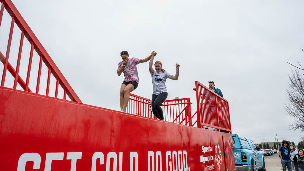 A far-off shot of two girls holding hands as they jump into the Polar Plunge tank.