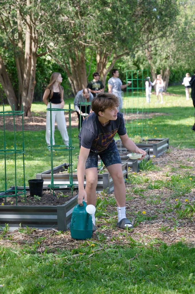 Willow Creek student lifting a watering can while working in their garden outside.