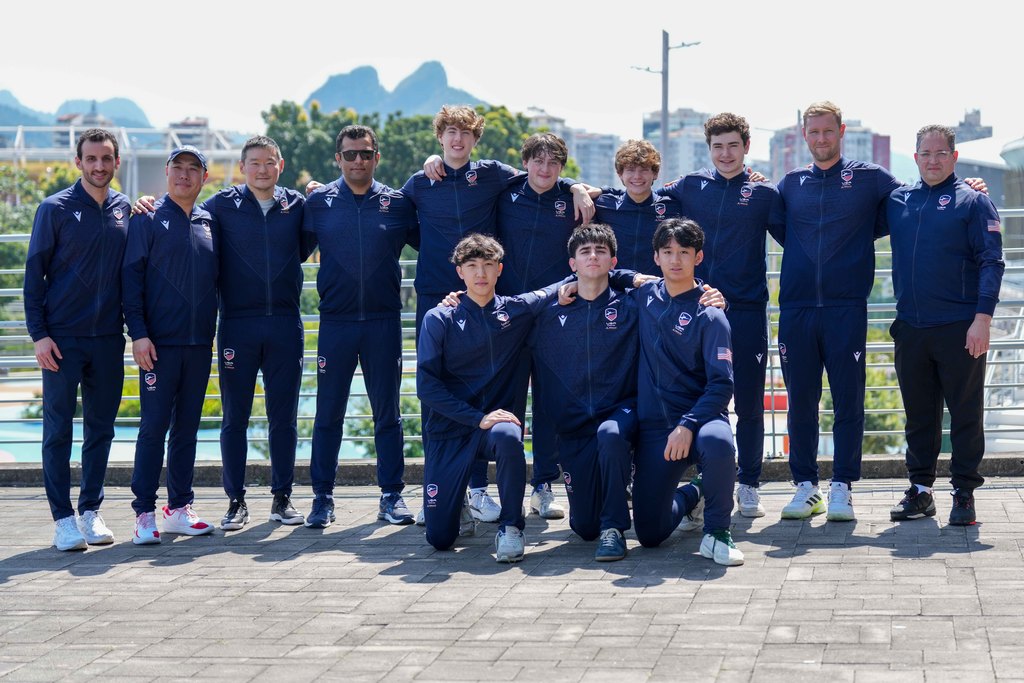 Team USA Epee team with their coaches posing for a photo in two rows.