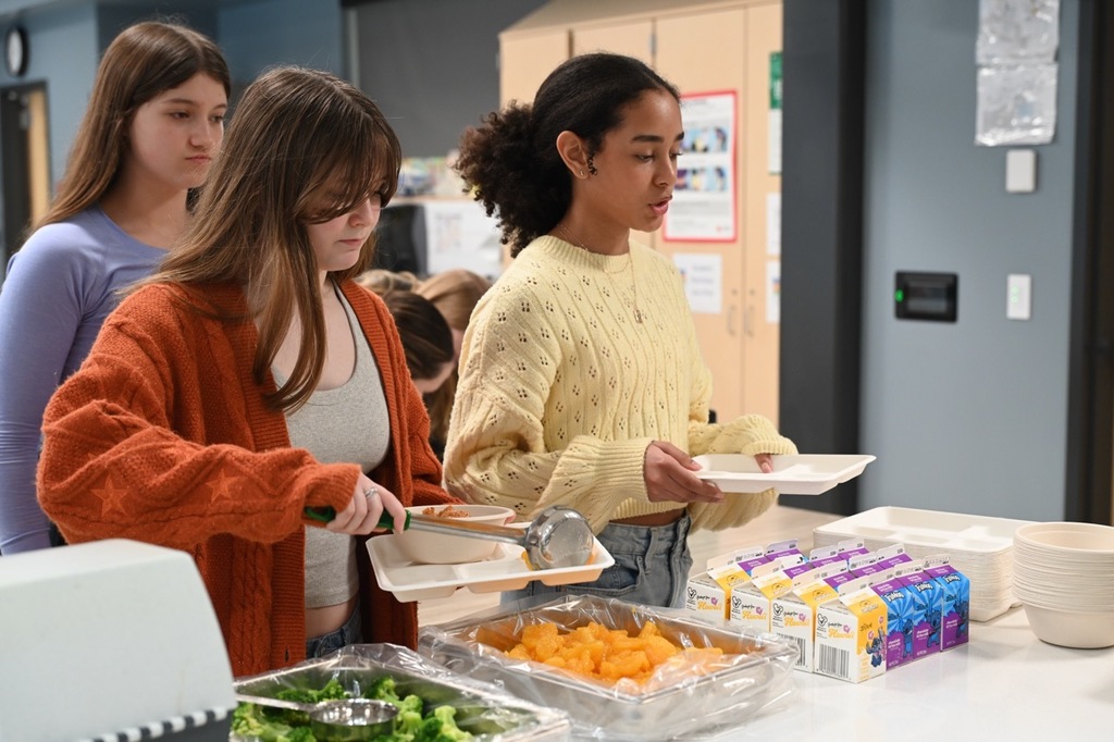 Students serving up their side dishes and grabbing milk from the food line.