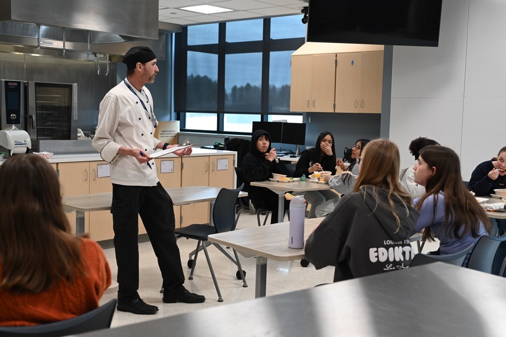 Students talking with Chef Travis about the lunch menus including what they like and dislike.