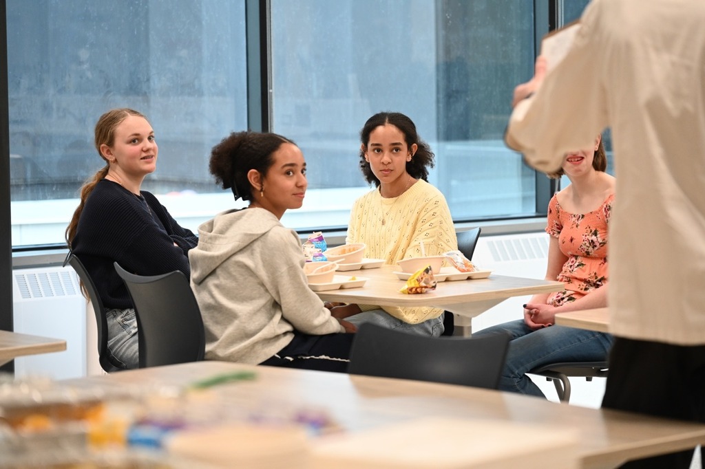 Students eating and listening to Chef Travis sitting at a table in the Dakota Test Kitchen.