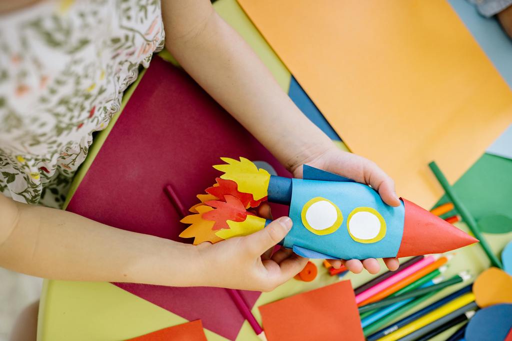 young child holding crafted rocket ship