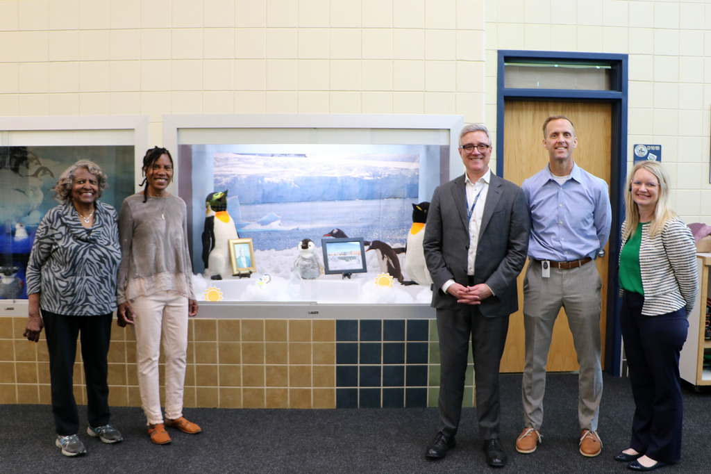 Joyce Gibbs, Leilani Gibbs, Kent Pekel, Mark Randall, and Kim Howards standing for a photo in front of the display of George W. Gibbs Jr. at Gibbs Elementary.