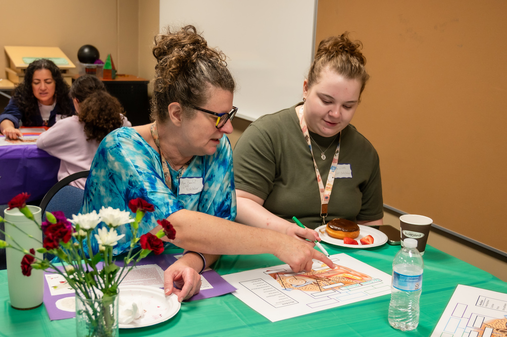 A woman and a student point to a diagram of the ear.