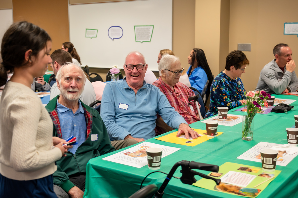 Three men from the Sertoma Club drink coffee and learn about the parts of the ear.