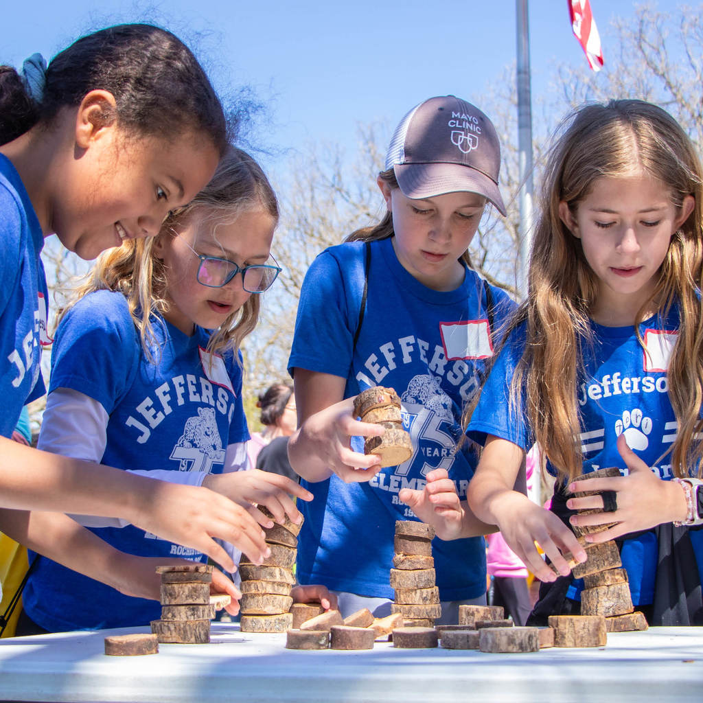 5th grades in Jefferson Elementary shirts race to stack pieces of wood the highest.