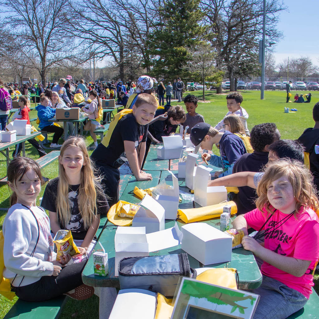 Gibbs Elementary students eat box lunches in the park.