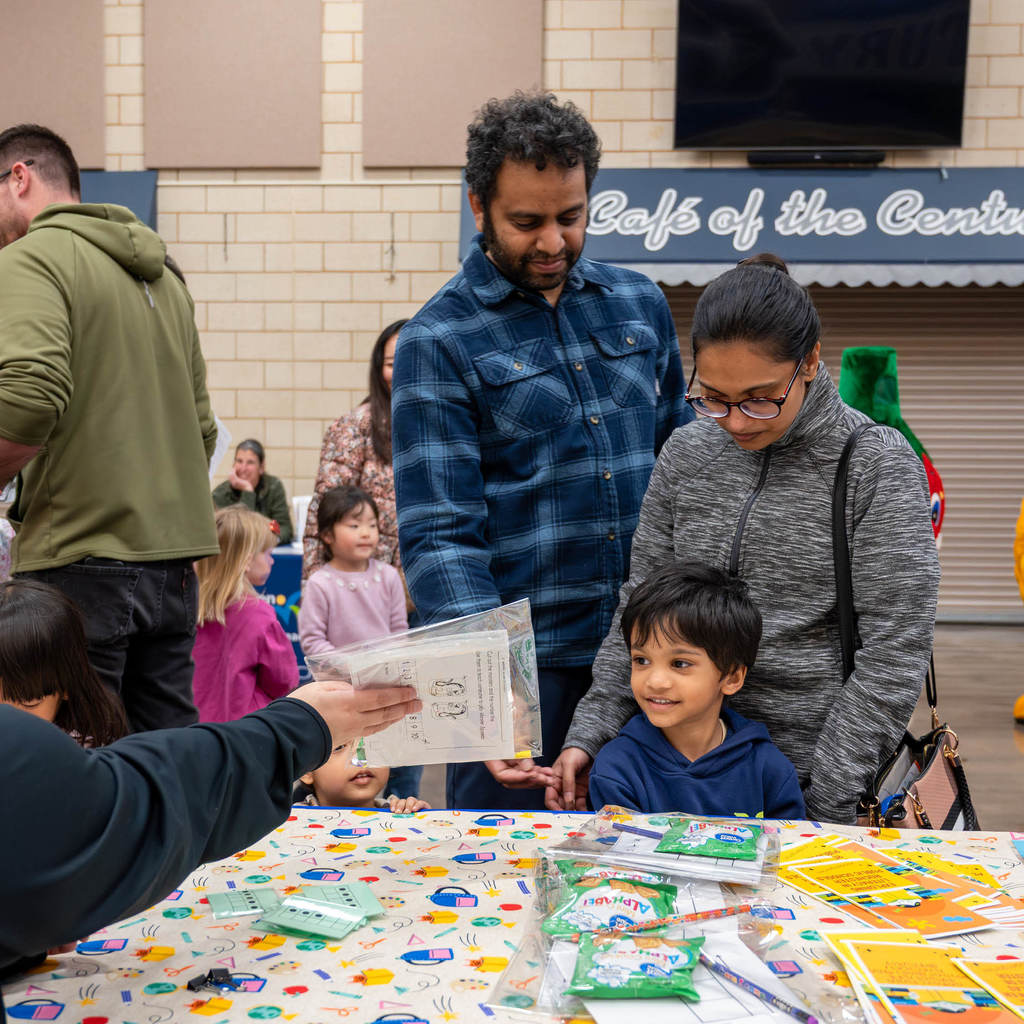 A young family at a booth are handed an activity packet.