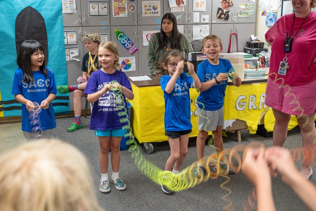 Four students playing with slinkys pulled across from their partners and laughing and smiling. 