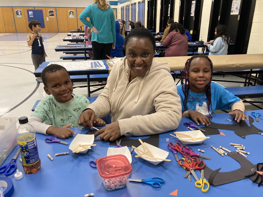 Family posing for a photo at the lunch table while doing a craft together. 